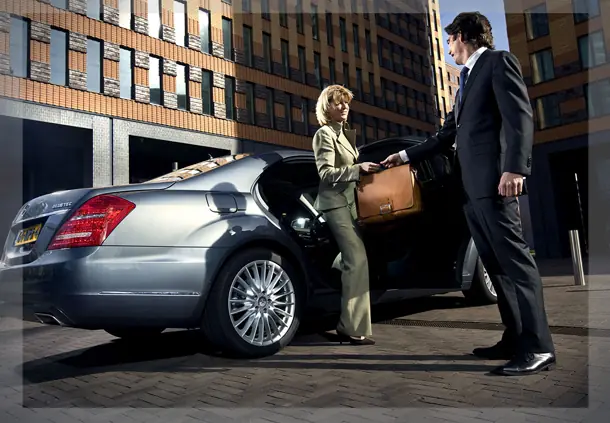 Driver greeting a passenger beside a saloon car